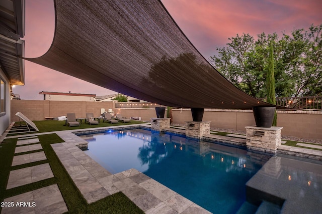 pool at dusk featuring a fenced in pool, a patio area, and a fenced backyard