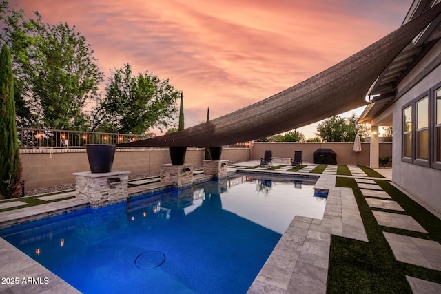 pool at dusk featuring a patio area, a fenced backyard, and a fenced in pool