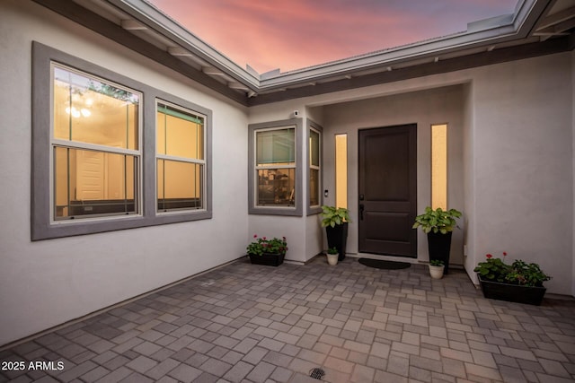 property entrance with a patio and stucco siding