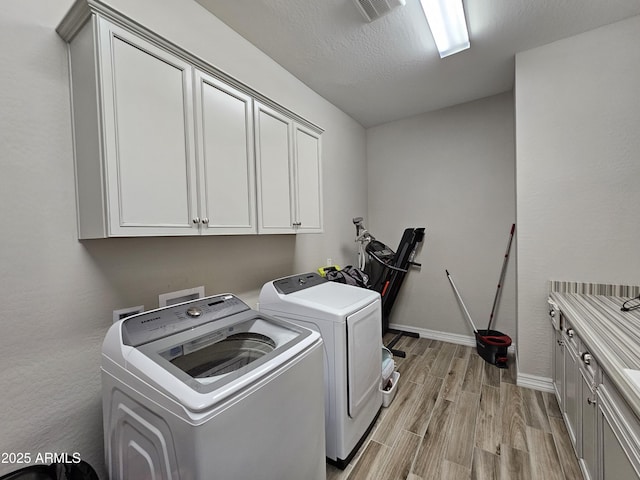 laundry room with cabinet space, visible vents, washer and clothes dryer, baseboards, and light wood-style flooring