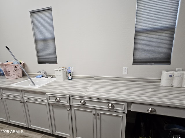 kitchen featuring gray cabinets, light countertops, and a sink