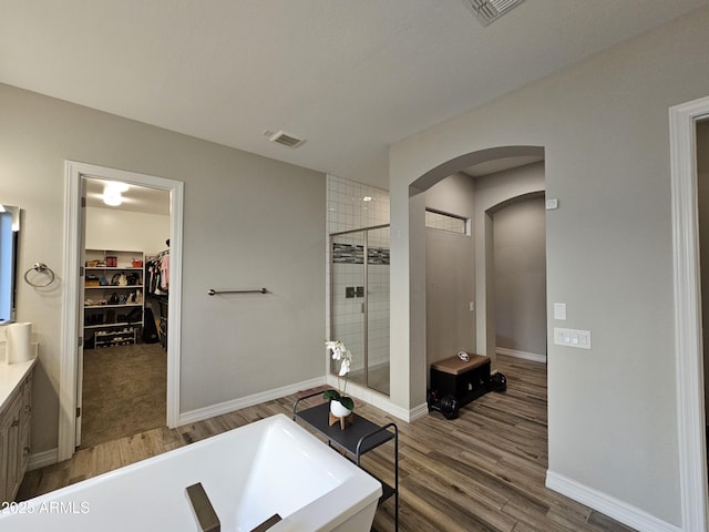 full bathroom featuring a tub to relax in, visible vents, a shower stall, and wood finished floors