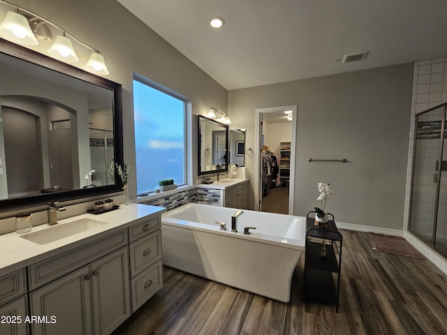 full bathroom featuring visible vents, a stall shower, a sink, wood finished floors, and a freestanding tub