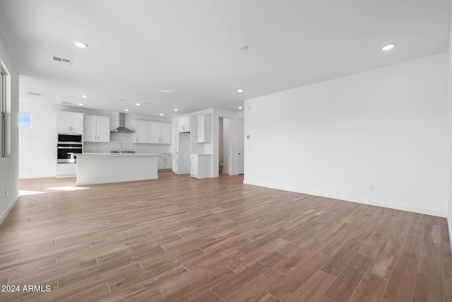 unfurnished living room with sink and light hardwood / wood-style flooring