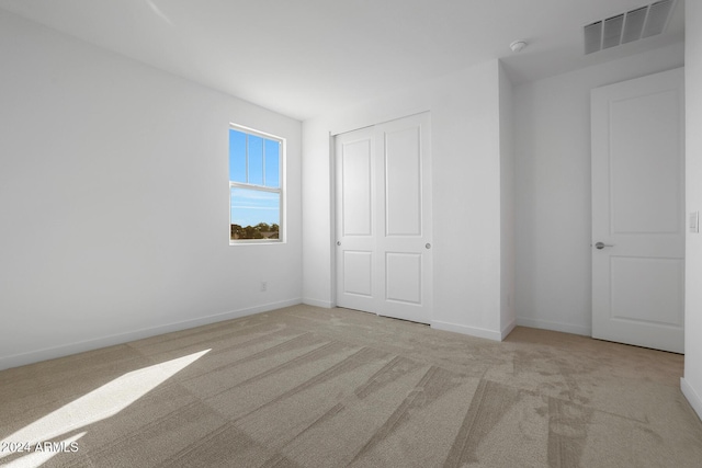 unfurnished bedroom featuring light colored carpet and a closet