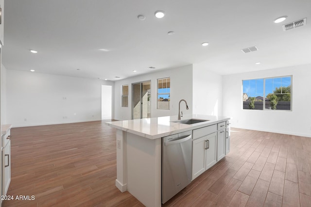 kitchen featuring dishwasher, sink, light hardwood / wood-style flooring, an island with sink, and white cabinets