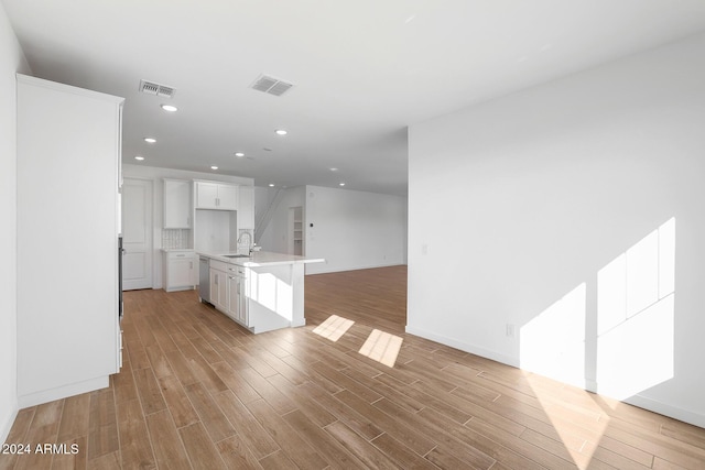 kitchen with light hardwood / wood-style floors, white cabinetry, and an island with sink