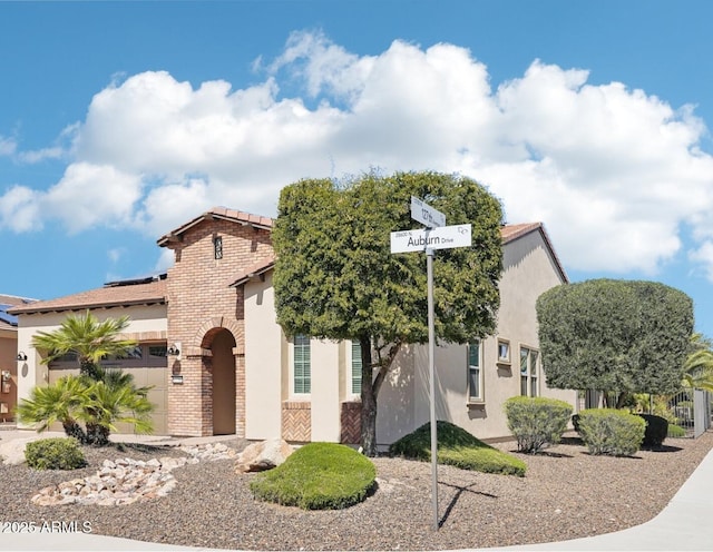 view of front of property with a garage, brick siding, and stucco siding