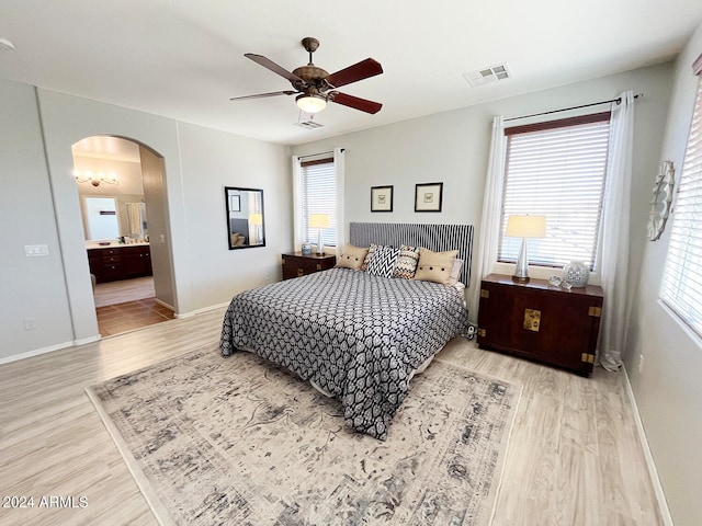 bedroom with multiple windows, connected bathroom, light hardwood / wood-style floors, and ceiling fan