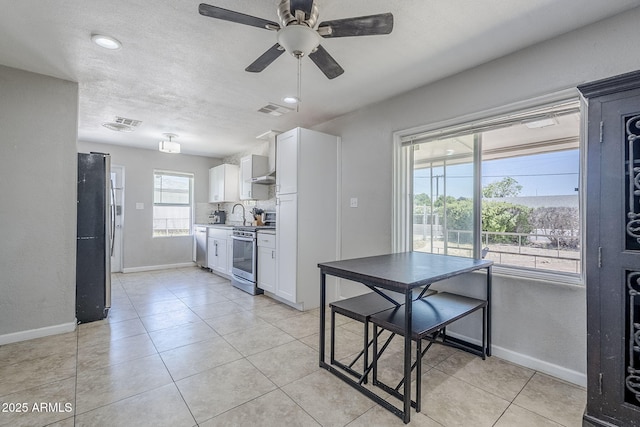 kitchen with white cabinets, baseboards, appliances with stainless steel finishes, and visible vents