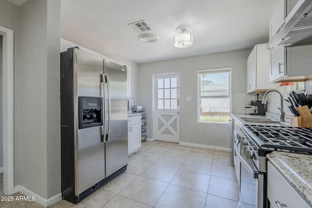 kitchen with under cabinet range hood, white cabinets, appliances with stainless steel finishes, and baseboards