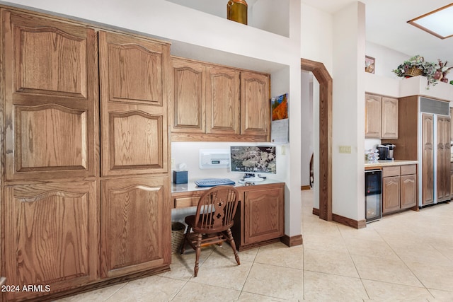 kitchen with wine cooler, built in desk, light tile patterned flooring, and paneled fridge