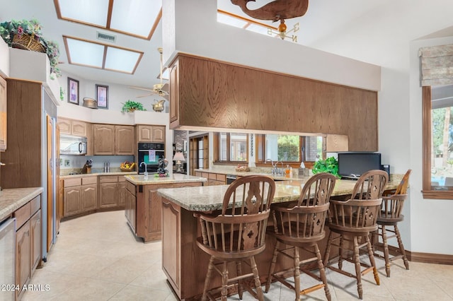 kitchen with light stone counters, a kitchen bar, light tile patterned flooring, and a center island