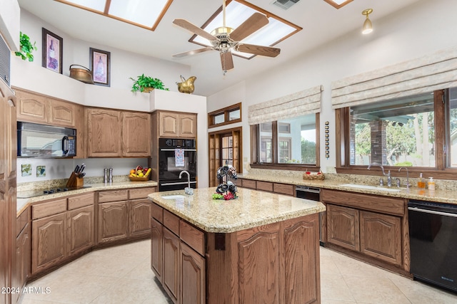 kitchen featuring light tile patterned flooring, a center island with sink, sink, and black appliances