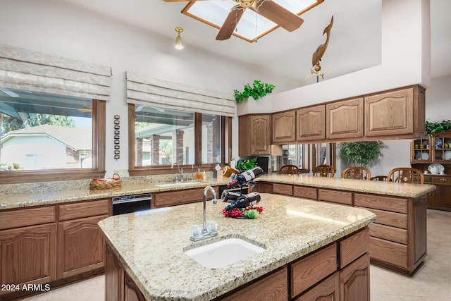 kitchen featuring light stone countertops, sink, and a kitchen island with sink