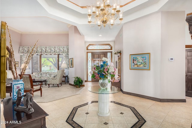 tiled foyer entrance featuring a chandelier, a raised ceiling, and crown molding