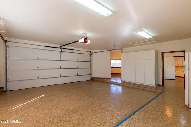 garage featuring a garage door opener and white refrigerator