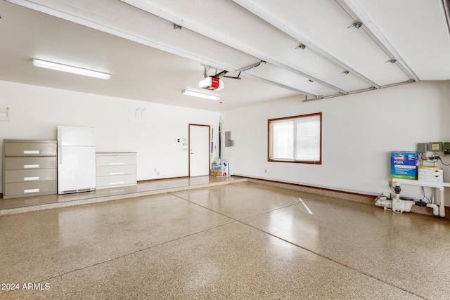 garage featuring white refrigerator and a garage door opener