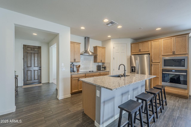 17618 W Medlock Dr, Litchfield Park, AZ 85340 - kitchen with appliances with stainless steel finishes, wall chimney exhaust hood, a sink, dark wood-type flooring, and a kitchen breakfast bar
