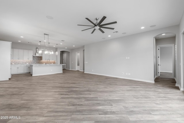 unfurnished living room featuring ceiling fan and light wood-type flooring