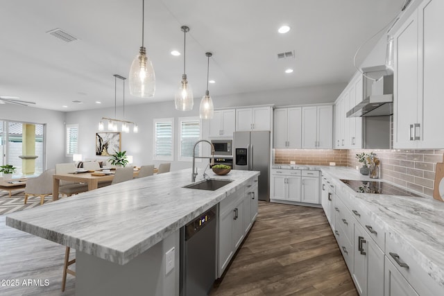 kitchen with decorative backsplash, sink, appliances with stainless steel finishes, an island with sink, and white cabinets