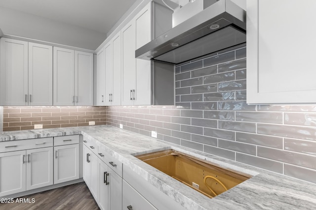 kitchen featuring decorative backsplash, white cabinetry, and wall chimney exhaust hood