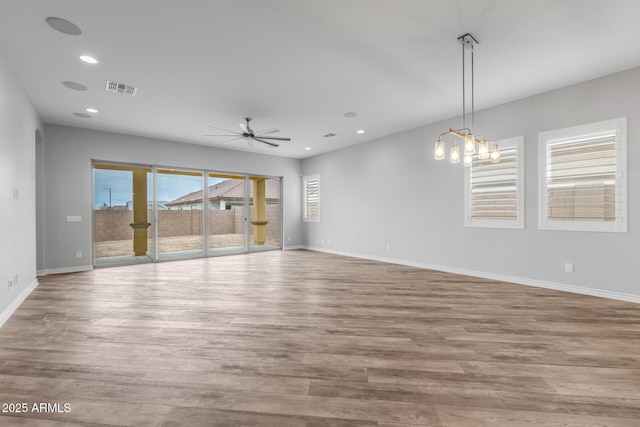 spare room with light hardwood / wood-style floors and ceiling fan with notable chandelier