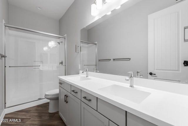 bathroom featuring toilet, a shower with shower door, hardwood / wood-style floors, and vanity