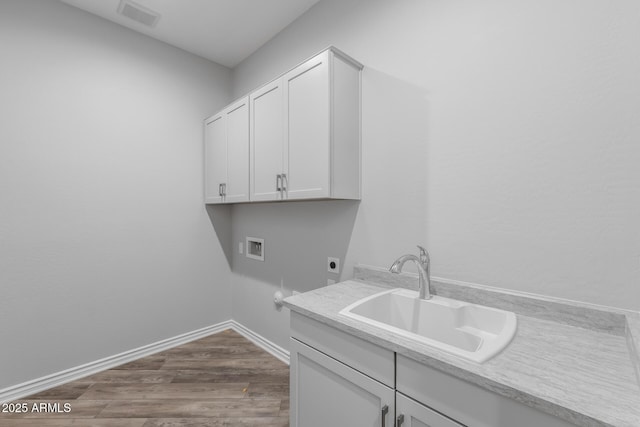 washroom with cabinets, washer hookup, sink, hookup for an electric dryer, and hardwood / wood-style flooring