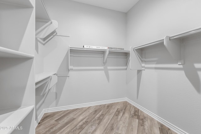 walk in closet with light hardwood / wood-style floors