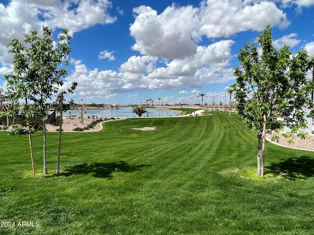 surrounding community with a water view and a yard