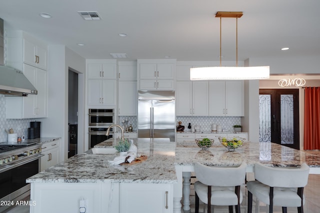 kitchen with decorative backsplash, a spacious island, sink, high quality appliances, and hanging light fixtures