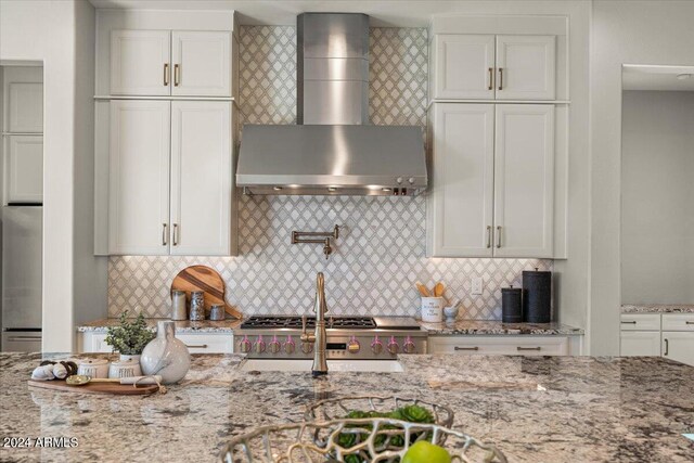 kitchen featuring tasteful backsplash, stainless steel fridge, light stone countertops, and wall chimney range hood