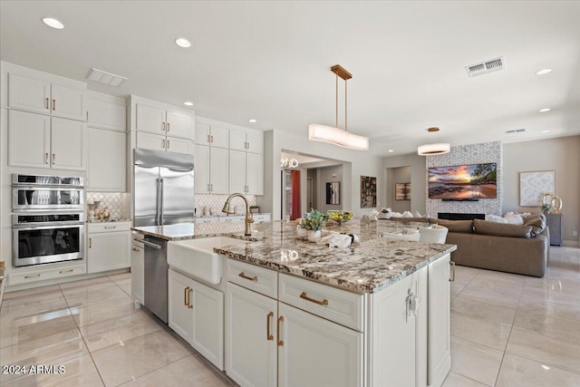 kitchen with backsplash, sink, an island with sink, white cabinetry, and stainless steel appliances