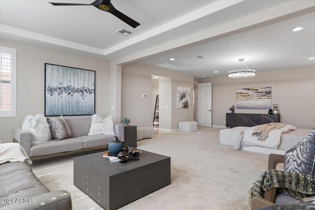 carpeted living room featuring ceiling fan with notable chandelier