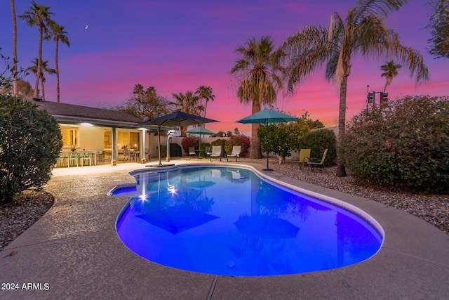 pool at dusk featuring a fenced in pool, a patio, and exterior bar