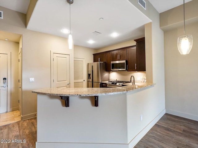 kitchen featuring dark wood-type flooring, decorative light fixtures, dark brown cabinets, and stainless steel appliances