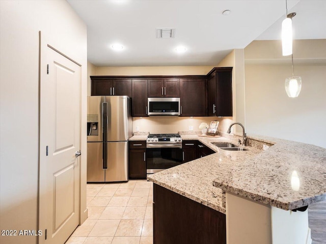 kitchen with appliances with stainless steel finishes, sink, pendant lighting, dark brown cabinets, and light tile patterned flooring