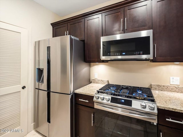 kitchen with stainless steel appliances, dark brown cabinetry, and light stone counters