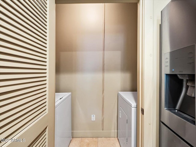 laundry area with washing machine and clothes dryer and light tile patterned floors