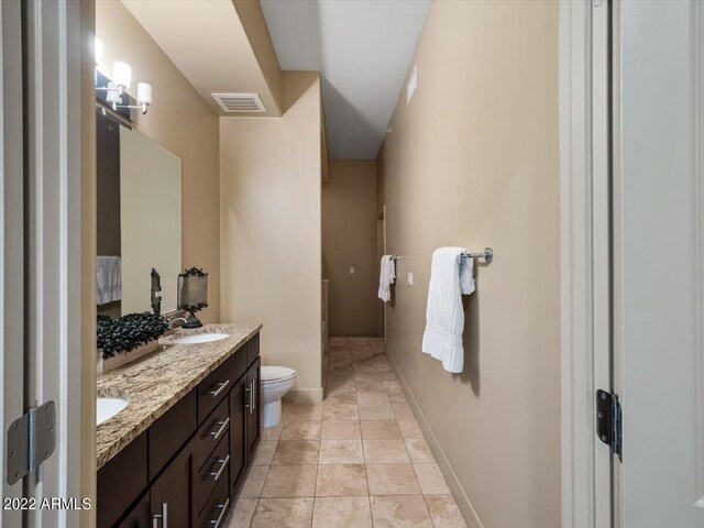 bathroom with toilet, tile patterned flooring, and double vanity