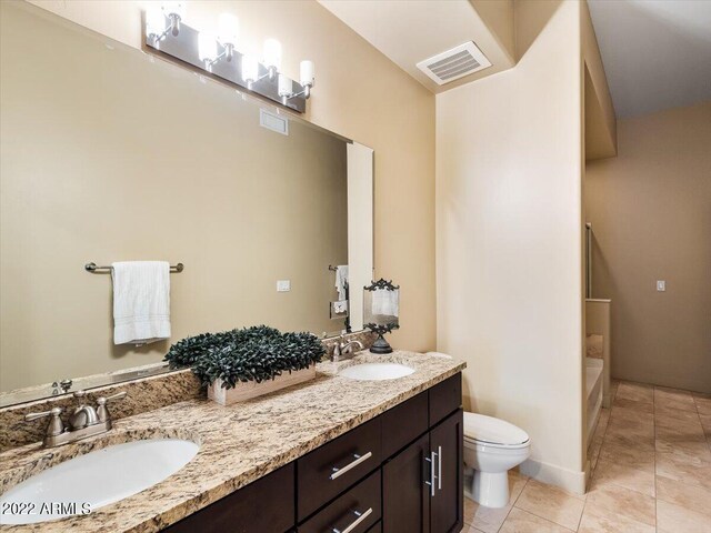 bathroom featuring dual vanity, toilet, and tile patterned floors