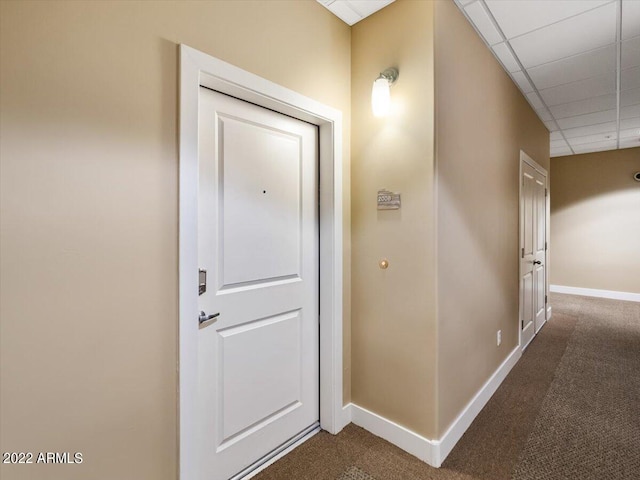 hall with a paneled ceiling and carpet