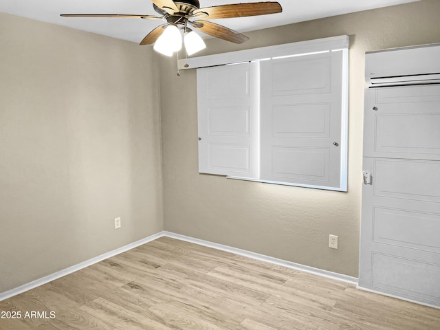 unfurnished bedroom with ceiling fan, a closet, a wall unit AC, and light wood-type flooring