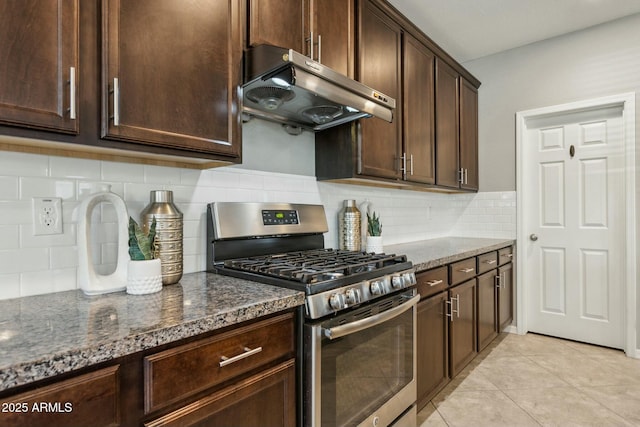 kitchen with dark stone countertops, light tile patterned floors, stainless steel range with gas cooktop, and dark brown cabinetry