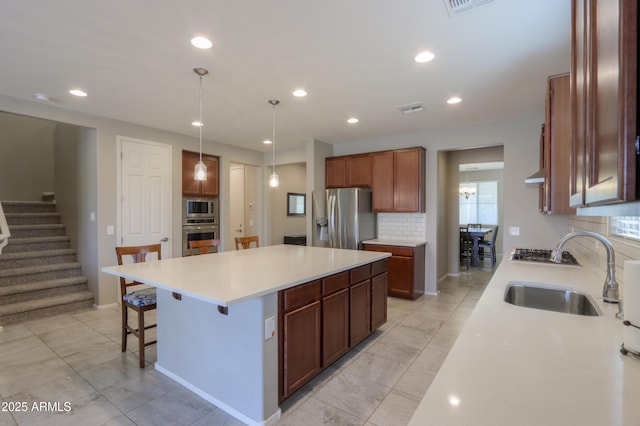 kitchen featuring backsplash, stainless steel appliances, sink, a center island, and hanging light fixtures