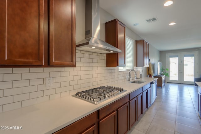 kitchen featuring decorative backsplash, stainless steel gas cooktop, sink, wall chimney range hood, and light tile patterned floors