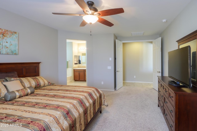 bedroom featuring light colored carpet, ensuite bath, and ceiling fan