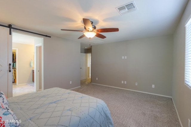 carpeted bedroom featuring ceiling fan, a barn door, and ensuite bath