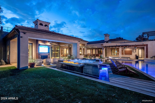 back house at dusk featuring a patio, an outdoor living space, a lawn, and ceiling fan